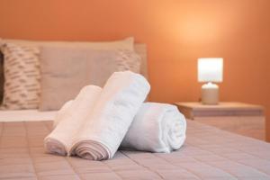 two rolls of white towels sitting on a bed at Kleos Apartment in Schisò