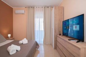 a bedroom with a large television and towels on a bed at Kleos Apartment in Schisò