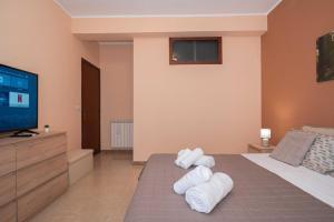 a bedroom with a bed and a tv and towels at Kleos Apartment in Schisò +38 photos