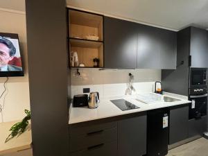 a kitchen with black cabinets and white counter tops at Ápice del bosque in Temuco +5 photos