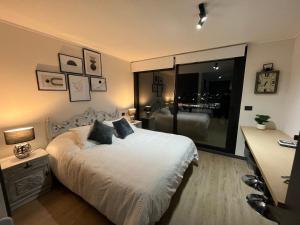 a bedroom with a white bed and a large window at Ápice del bosque in Temuco