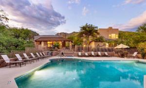 a swimming pool with chairs and a house at Our Mountain View in Tucson