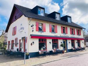 a white building with red windows and tables on a street at De La Frontière Bed & Borrelbistro in Slenaken
