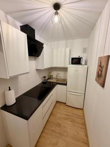 a white kitchen with a sink and a refrigerator at Muranów Rooms Warsaw in Warsaw