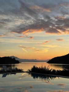 a sunset on a lake with a boat in the water at Santa Clara Hotel in Paraty
