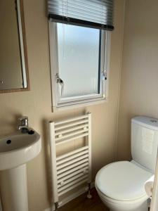 a bathroom with a toilet and a sink and a window at Merryfield and Sandfields in Chapel Saint Leonards +32 photos