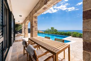 a patio with a wooden table and chairs and a swimming pool at Villa Azzurra in Krstac