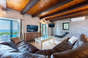 a living room with a leather couch and a television at Villa Azzurra in Krstac