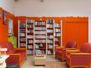 a library with orange chairs and book shelves filled with books at Chalet HABIA TXIKIA 4 pers, neuf, sur Hasparren, calme, avec piscine et climatisation, Pays Basque in Hasparren +6 photos