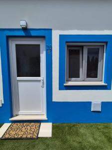 a blue house with a white door and two windows at Casa do Barco in Odiáxere