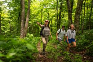 three people walking on a trail in the woods at The Speckled Trout Outpost in Damascus