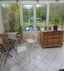 a porch with a table and chairs and a dresser at gite du canal in Ormoy