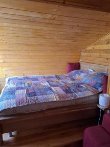a bed in a room with a wooden wall at Cabana trenulețelor in Lunca Mare