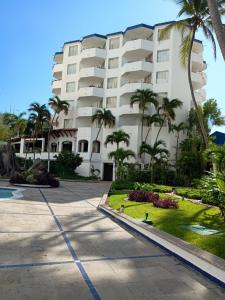 ein großes weißes Gebäude mit Palmen davor in der Unterkunft Hotel Acapulco Malibu in Acapulco