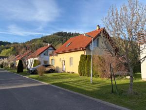 a yellow house with a red roof on a street at Villy Vlašky in Bešeňová