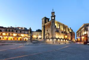 un antiguo edificio con una torre de reloj por la noche en Eurostars Palacio de Santa Marta, en Trujillo