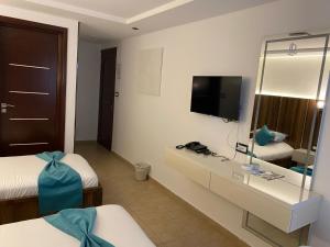 a hotel room with two beds and a television at Impavid Hotel in Gabès
