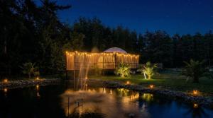 a building lit up at night next to a pond at Vilodge in Charrúa +1 photo