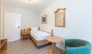 a room with a bed and a chair and a mirror at Hotel Keller in Kreuztal
