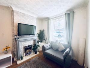 a living room with a chair and a television and a fireplace at Lonsdale Terrace - 3 Bedrooms - Sleeps 6 in Workington