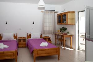a room with two beds and a table and a kitchen at Fay's Studios Leros in Lakkíon