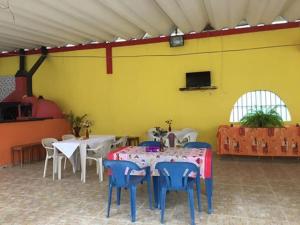 a room with tables and chairs and a yellow wall at Suítes Recanto Renascer in Caraguatatuba