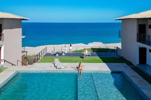 a swimming pool with the ocean in the background at Sea View + Pool | Cliffs Mar 209 in Pipa