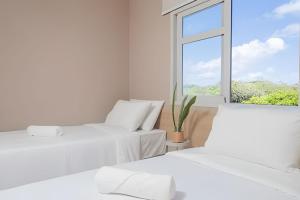 two beds in a room with a window at Sea View + Pool | Cliffs Mar 209 in Pipa +23 photos