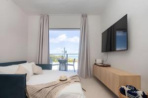 a bedroom with a bed and a television and a balcony at Sea View + Pool | Cliffs Mar 209 in Pipa