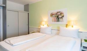a bedroom with two beds with white sheets at Hotel Keller in Kreuztal +8 photos