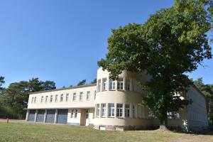 a large building with a tree in front of it at Pension Alte Flugleitung in Stendal