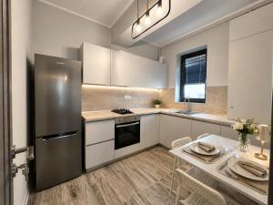 a kitchen with a stainless steel refrigerator and a table at AVI GARDEN Apartments in Constanţa