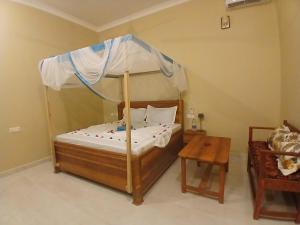 a bedroom with a canopy bed and a table at Sun house kendwa beach in Kendwa