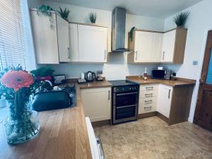 a kitchen with white cabinets and a vase of flowers at Lonsdale Terrace - 3 Bedrooms - Sleeps 6 in Workington