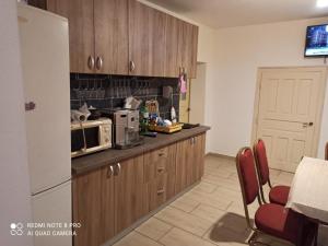 a kitchen with wooden cabinets and a white refrigerator at Pensiunea Solo in Dretea