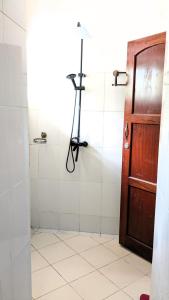 a bathroom with a shower with a door and a tripod at The Hub Train House Hakuna Matata in Zanzibar City
