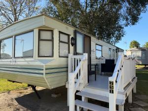 a green and white caravan with a porch and stairs at Jackson Home from Home Holidays in Little Clacton