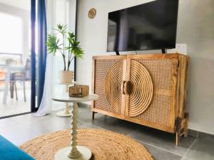 a living room with a tv and a table at Le léza - Terrasse et plage à 1 min in Les Trois-Îlets