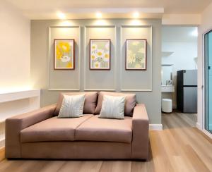 a couch in a living room with three pictures on the wall at Impact poppula P1 by เจี๊ยบ in Thung Si Kan