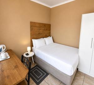 a small bedroom with a bed and a table at Gaecho Guesthouse in Thaba Nchu +2 photos