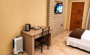 a small desk in a room with a bed and a television at Gaecho Guesthouse in Thaba Nchu