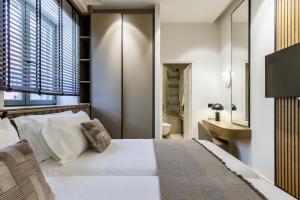 a bedroom with a white bed and a bathroom at Cavo Mare Skopelos in Skopelos Town