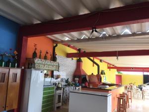 a kitchen with a refrigerator and tables and chairs at Suítes Recanto Renascer in Caraguatatuba