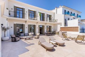 a patio with chairs and tables and a building at Cavo Mare Skopelos in Skopelos Town