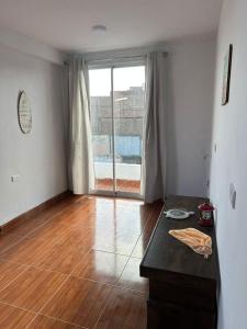a living room with a table and a large window at Mamá María Surf House in Puerto Chicama