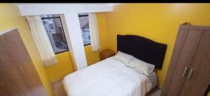 a bedroom with a white bed and a yellow wall at Cozy Apartment in PUNO in Puno