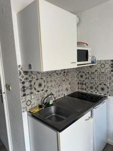 a small kitchen with a sink and a microwave at Les logis de Paray - app 211 in Paray-le-Monial