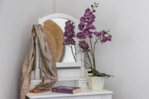 a shelf with a mirror and purple flowers on it at Artemis Cozy Home in Péran Triovasálos +17 photos