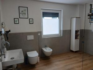 a bathroom with a toilet and a sink and a window at Ferienwohnung Buchenblatt in Simmerath +15 photos