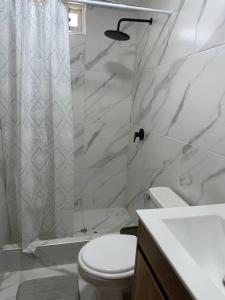 a white bathroom with a toilet and a shower at Mamá María Surf House in Puerto Chicama